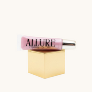Pink lip gloss tube with gold cap on a marble surface