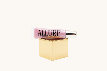 Pink lip gloss tube with gold cap on a marble surface