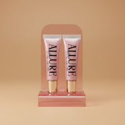 Two Allure lip gloss tubes on a marble surface