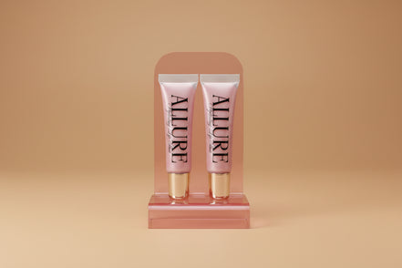 Two Allure lip gloss tubes on a marble surface