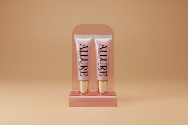 Two Allure lip gloss tubes on a marble surface