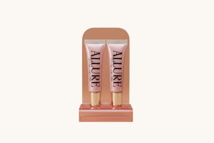 Two Allure lip gloss tubes on a marble surface