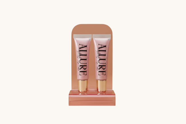 Two Allure lip gloss tubes on a marble surface