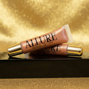 Two Allure lip gloss tubes on a marble surface