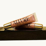 Two Allure lip gloss tubes on a marble surface