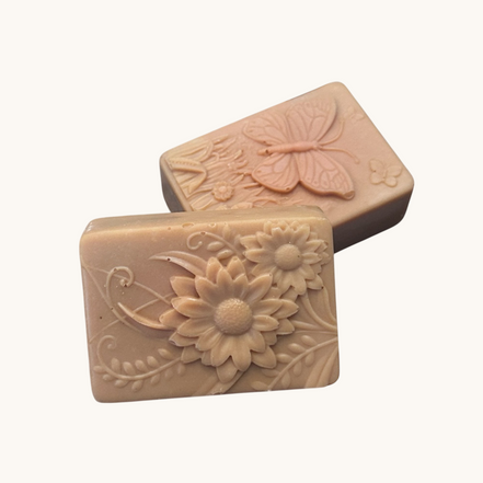 Creation Essential's Natural Body Tropical Fusion soap bars with embossed floral and butterfly designs on a white base