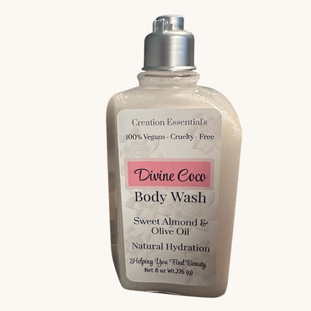Creation Essential's Natural Body Divine Coco hydrating body wash in a clear bottle set among white daisies.