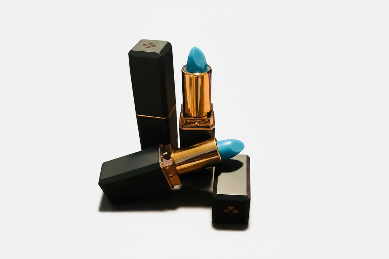 Two lipsticks with black and gold cases and blue caps on a white background